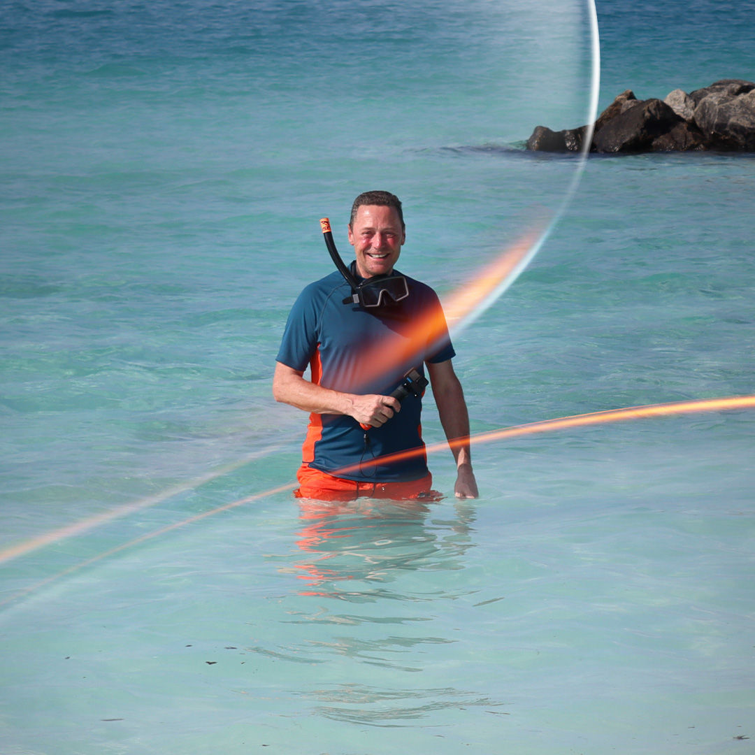 Man stood in the sea wearing snorkeling gear.